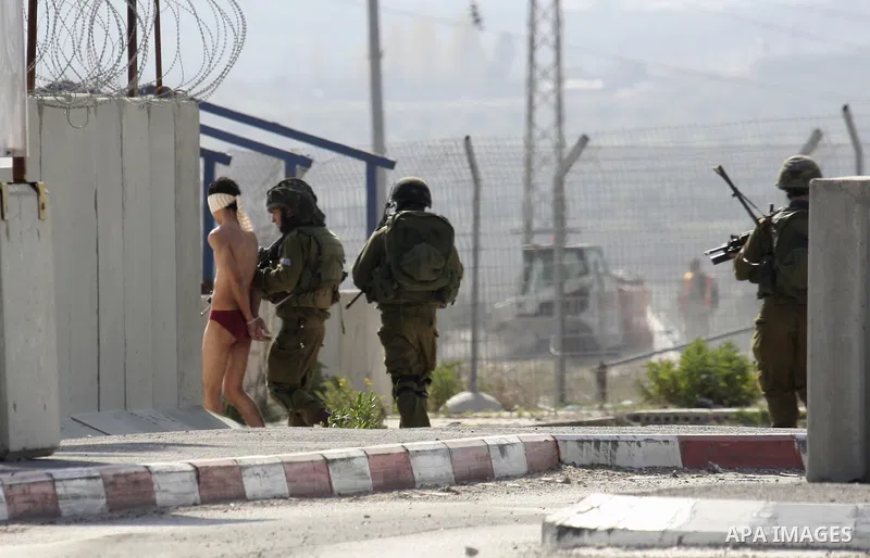 Israeli soldiers lead a stripped, blindfolded and handcuffed Palestinain youth to the back of the Huwara checkpoint after they suspected he was carrying explosives along with another boy near the West Bank city of Nablus...