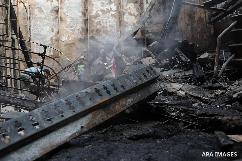 Smokes rises as an Egyptian protester helps extinguish smoldering valuable books and documents salvaged from the two story building of the Egyptian Scientific Complex after it was almost gutted by fire which broke out du...