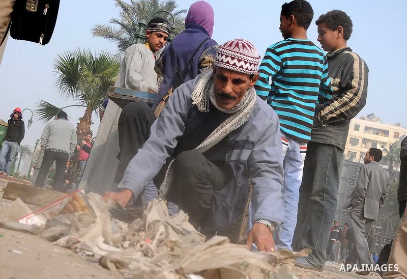 Egyptian protesters gather debris in a street by the Institute of Egypt, which was torched during protests, in central Cairo on December 20, 2011. Clashes between Egyptian security forces and protesters demanding an end...