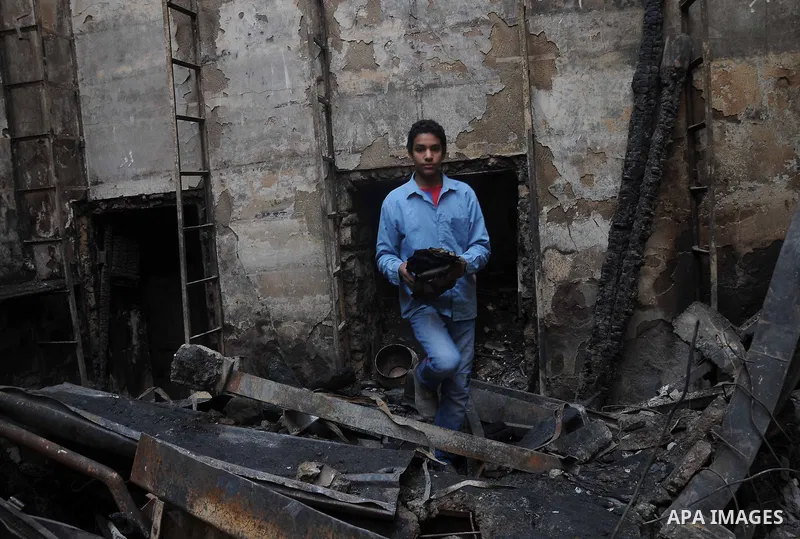 Smokes rises as an Egyptian protester helps extinguish smoldering valuable books and documents salvaged from the two story building of the Egyptian Scientific Complex after it was almost gutted by fire which broke out du...