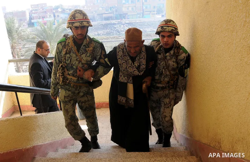 An old man is helped by army soldiers before casting his vote during the second round of parliamentary run-off elections at Imbaba in Giza, on the outskirts of Cairo December 21, 2011. Egyptians returned to the polls on...