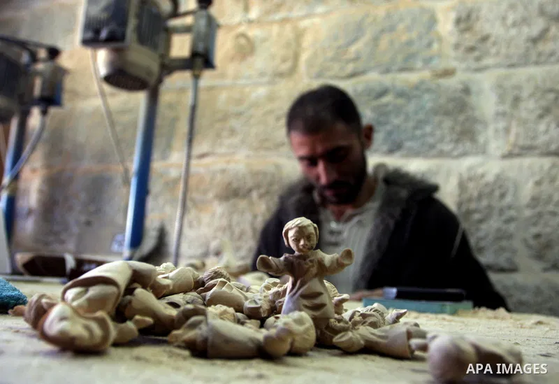 A Palestinian wood carver works on a nativity figurines are stored in an olive wood factory in the West Bank town of Bethlehem, ahead of Christmas,Thursday, Dec. 22, 2011. Photo by Issam Rimawi