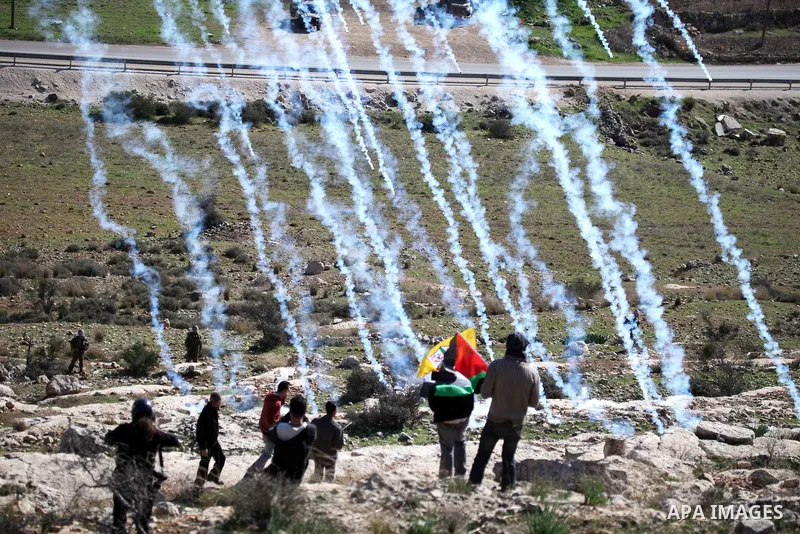 Palestinian and left-wing Israeli demonstrators run from a tear gas grenade fired by Israeli security officers during clashes at a weekly protest against a nearby Jewish settlement, in the West Bank village of Nabi Saleh...