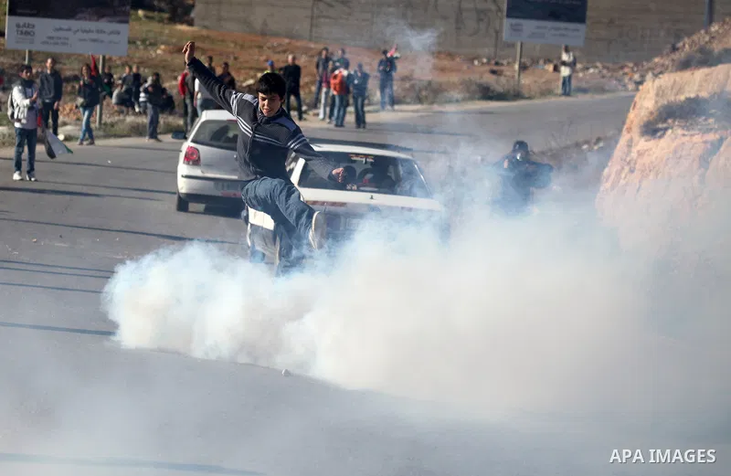 A Palestinian demonstrator hurls tear gas canister towards Israeli security forces during clashes at a weekly protest against a nearby Jewish settlement, in the West Bank village of Nabi Saleh, near Ramallah December 23,...