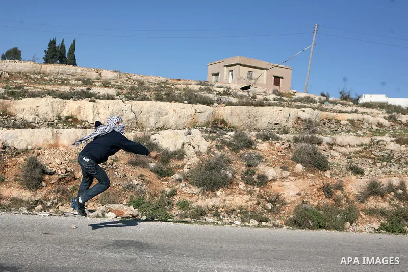 A Palestinian youth uses a sling to throw a stone toward Israeli soldiers during clashes at a weekly protest in the West Bank village of Nabi Saleh, near Ramallah, December 23, 2011.