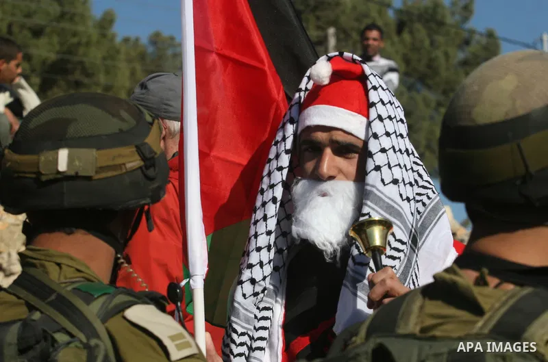 An Israeli soldier pushes back a demonstrator dressed as Santa Claus and holding a Palestinian flag during a protest against the controversial Israeli barrier in the West Bank village of al-Masara near Bethlehem December...