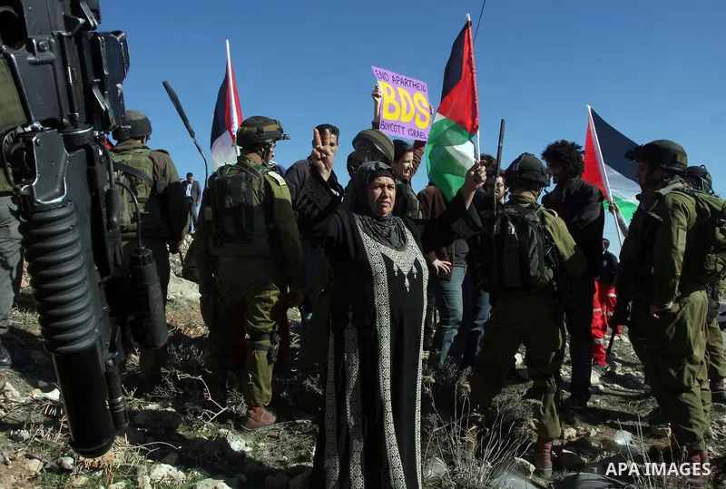 A young demonstrator dressed as Santa Claus stands near Israeli soldiers standing guard during a protest against the controversial Israeli barrier in the West Bank village of al-Masara near Bethlehem December 23, 2011. P...