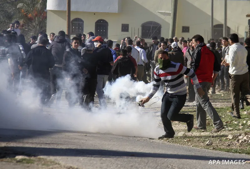 Palestinian protest hurl in tear gas at Israeli security forces ,during a protest in the village of Kufr Qaddum near the Israeli settlement of Kdumim, in the northern West Bank, Friday, Dec. 23, 2011 . Photo by Wagdi Esh...