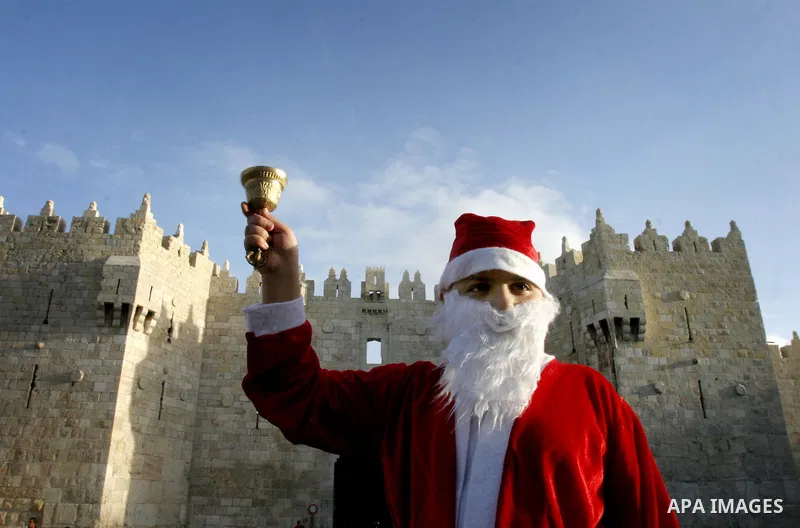 A Palestinian boy dressed-up in a Santa Claus costume walks on Jerusalem's Old City walls on December 24, 2011. Photo by Mahfouz Abu Turk