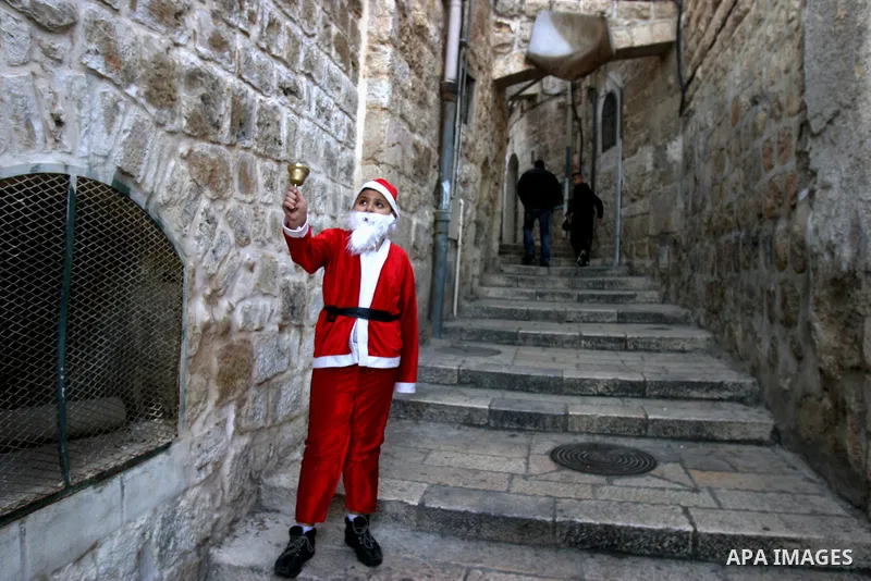 A Palestinian boy dressed-up in a Santa Claus costume walks on Jerusalem's Old City walls on December 24, 2011. Photo by Mahfouz Abu Turk