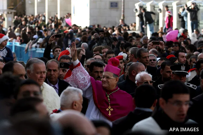 The head of the Roman Catholic Church in the Holy Land, the Latin Patriarch of Jerusalem Fuad Twal waves as he arrives to bless the crowd outside the Church of the Nativity in the Biblical West Bank city of Bethlehem, be...