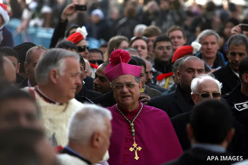 The head of the Roman Catholic Church in the Holy Land, the Latin Patriarch of Jerusalem Fuad Twal waves as he arrives to bless the crowd outside the Church of the Nativity in the Biblical West Bank city of Bethlehem, be...