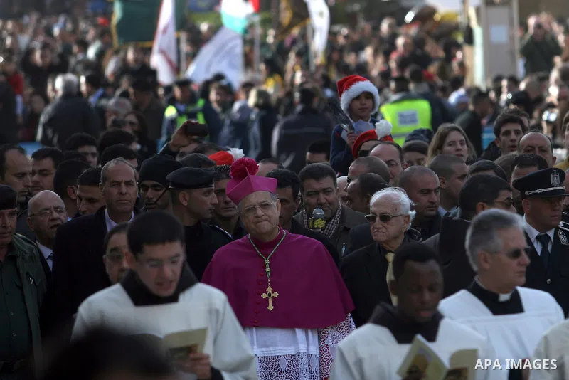 The head of the Roman Catholic Church in the Holy Land, the Latin Patriarch of Jerusalem Fuad Twal waves as he arrives to bless the crowd outside the Church of the Nativity in the Biblical West Bank city of Bethlehem, be...