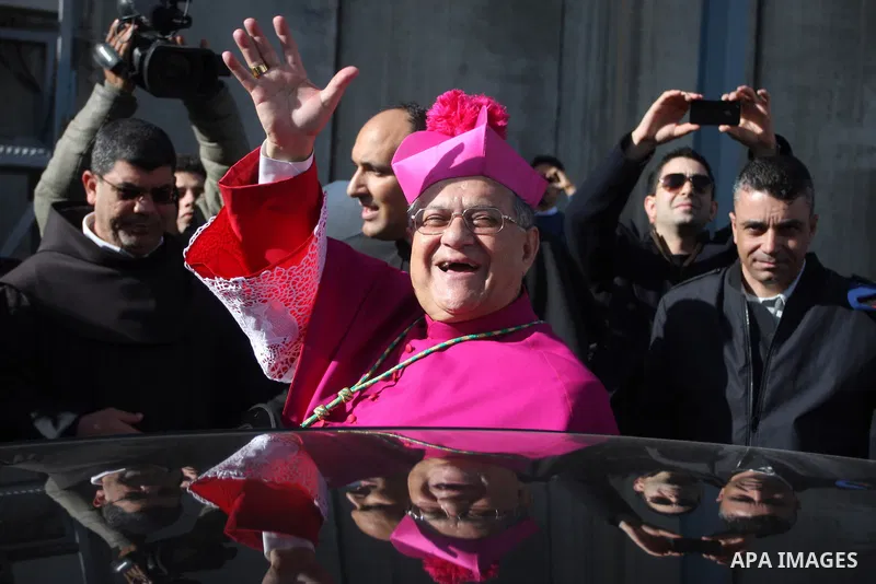 The Latin Patriarch of Jerusalem Fouad Twal waves near the controversial Israeli barrier as he heads to the Church of the Nativity to attend Christmas celebrations in the West Bank town of Bethlehem December 24, 2011.Pho...