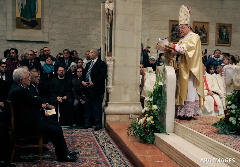 Palestinian President Mahmoud Abbas, left listens to Latin Patriarch of Jerusalem Fouad Twal hold the Christmas midnight Mass at the Church of the Nativity, traditionally believed to be the birthplace of Jesus Christ, in...
