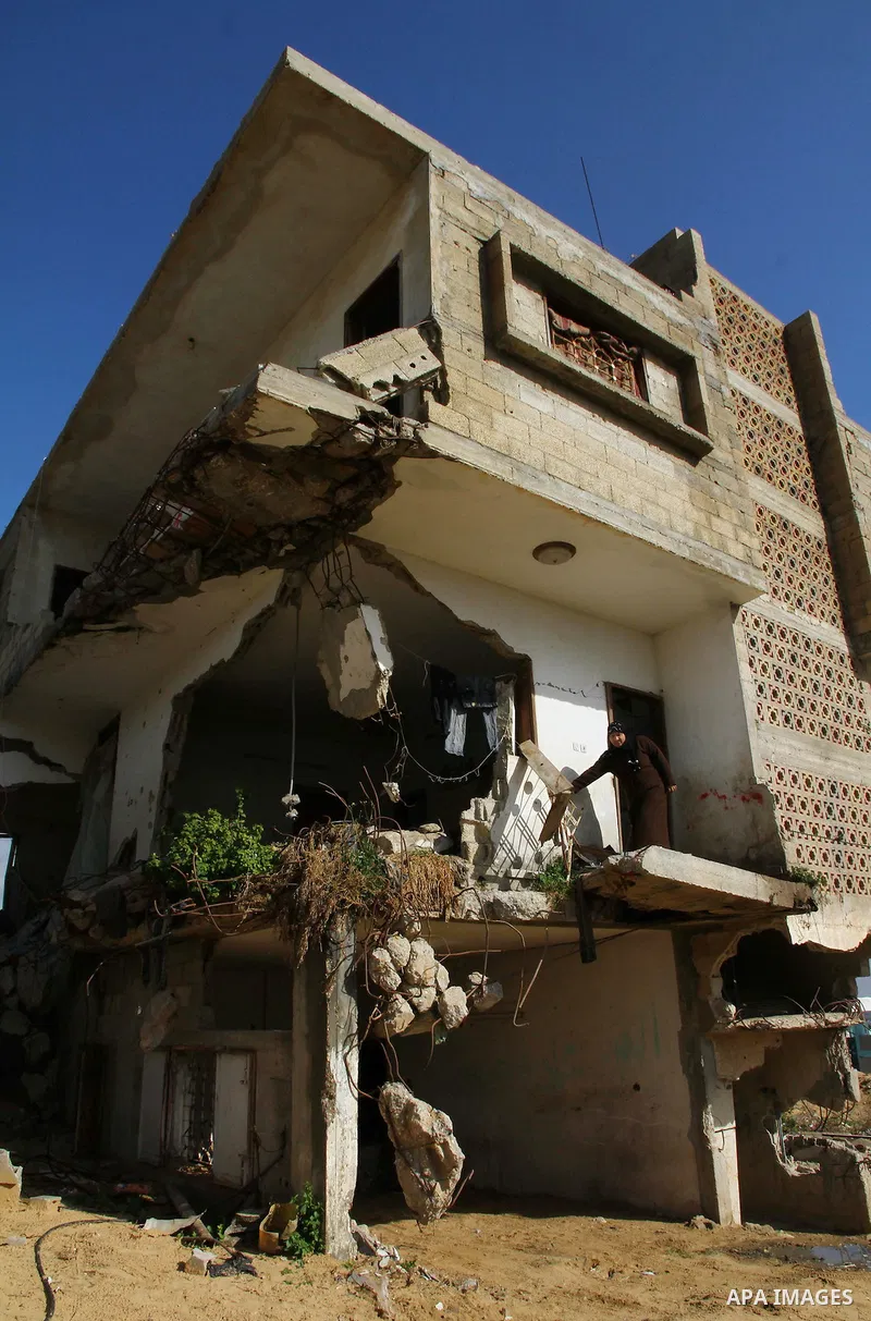 Palestinian woman stands in her house destroyed during the three-week offensive Israel launched before three years, in Gaza City, on 26 December 2011. which was damaged during Israel's three-week offensive three years ag...