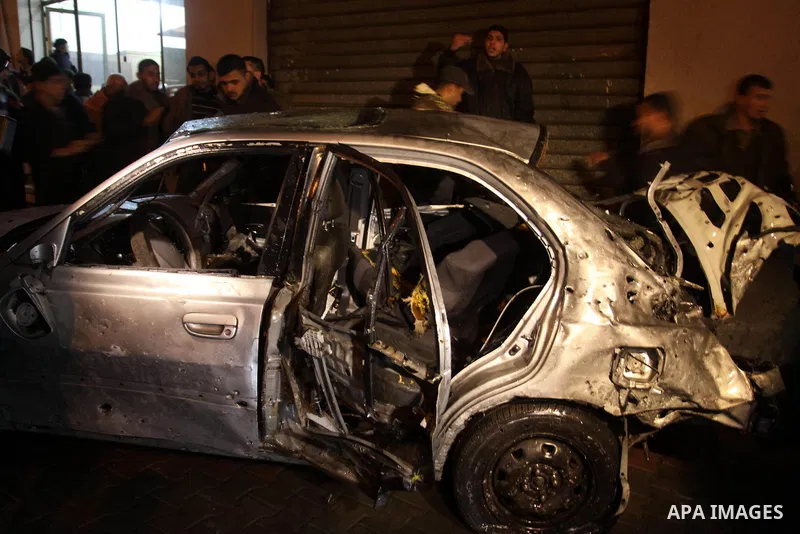 Palestinians look at a car damaged in an explosion, apparently caused by an Israeli air strike, in the northern Gaza Strip December 27, 2011. An explosion, apparently caused by an Israeli air strike, killed one person an...