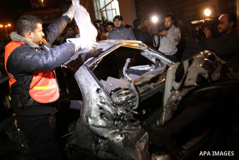 Palestinians look at a car damaged in an explosion, apparently caused by an Israeli air strike, in the northern Gaza Strip December 27, 2011. An explosion, apparently caused by an Israeli air strike, killed one person an...