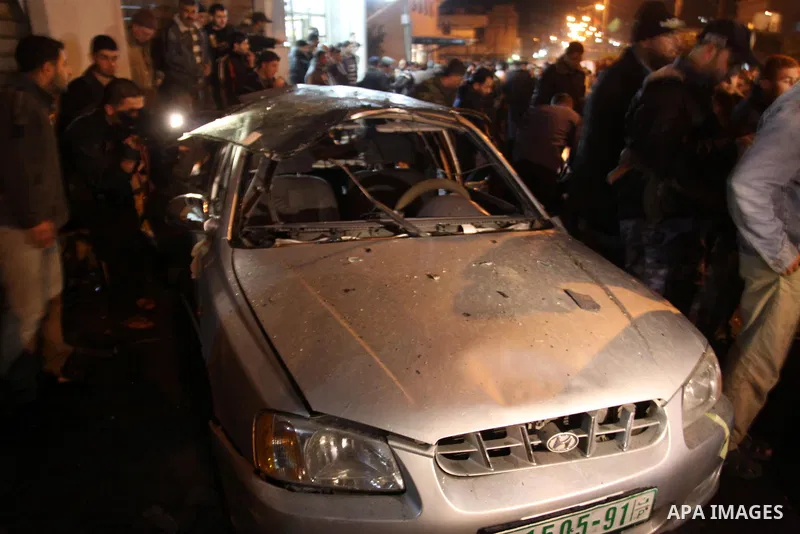 Palestinians look at a car damaged in an explosion, apparently caused by an Israeli air strike, in the northern Gaza Strip December 27, 2011. An explosion, apparently caused by an Israeli air strike, killed one person an...