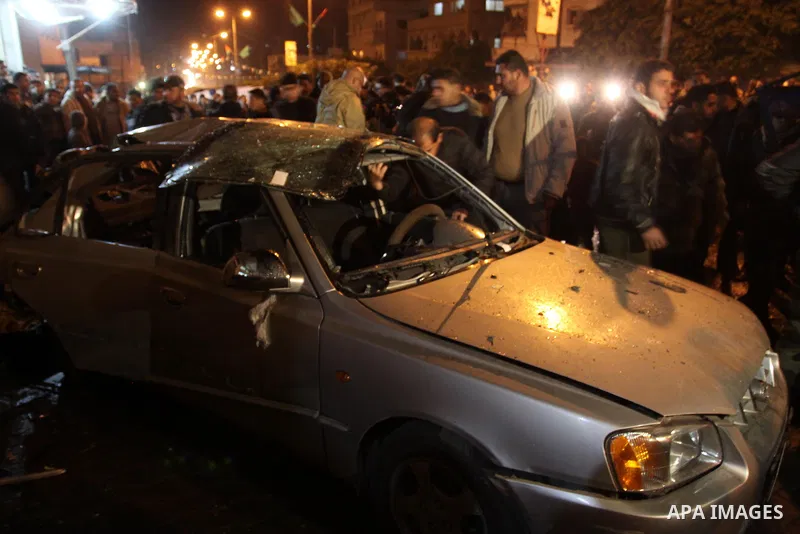 Palestinians look at a car damaged in an explosion, apparently caused by an Israeli air strike, in the northern Gaza Strip December 27, 2011. An explosion, apparently caused by an Israeli air strike, killed one person an...