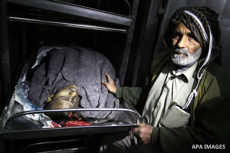 A man stands next to the body of a Palestinian killed in an explosion, apparently caused by an Israeli air strike, at a hospital in the northern Gaza Strip December 27, 2011. An explosion, apparently caused by an Israeli...