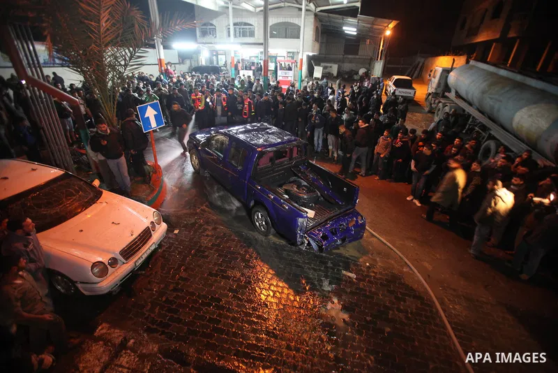 Palestinians gather around a vehicle targeted in a second Israeli air strike in Gaza City on December 27, 2011. Photo by Ali Jadallah