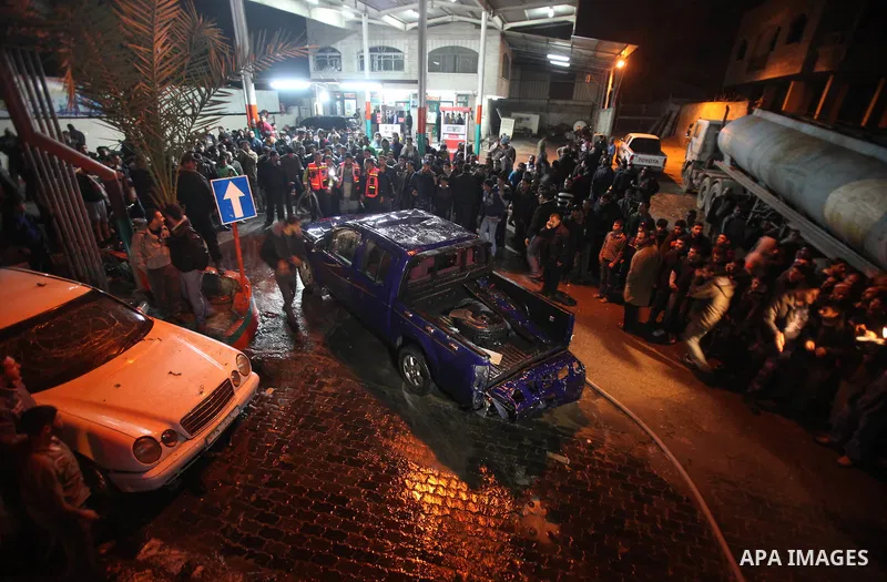 Palestinians gather around a vehicle targeted in a second Israeli air strike in Gaza City on December 27, 2011. Photo by Ali Jadallah