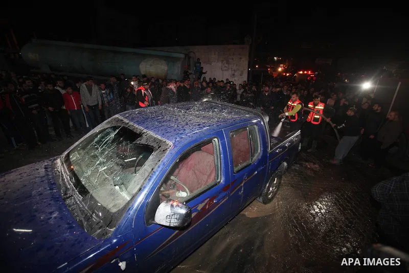 Palestinians gather around a vehicle targeted in a second Israeli air strike in Gaza City on December 27, 2011. Photo by Ali Jadallah