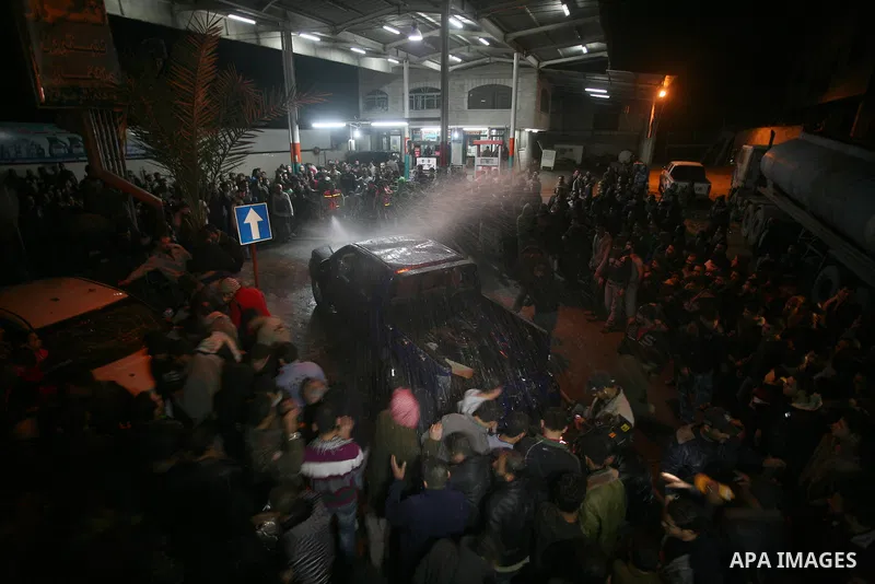 Palestinians gather around a vehicle targeted in a second Israeli air strike in Gaza City on December 27, 2011. Photo by Mahmud Nassar