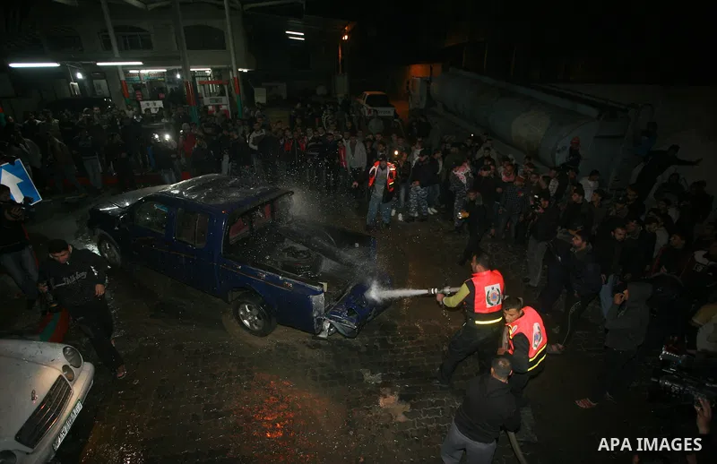 Palestinians gather around a vehicle targeted in a second Israeli air strike in Gaza City on December 27, 2011. Photo by Mahmud Nassar