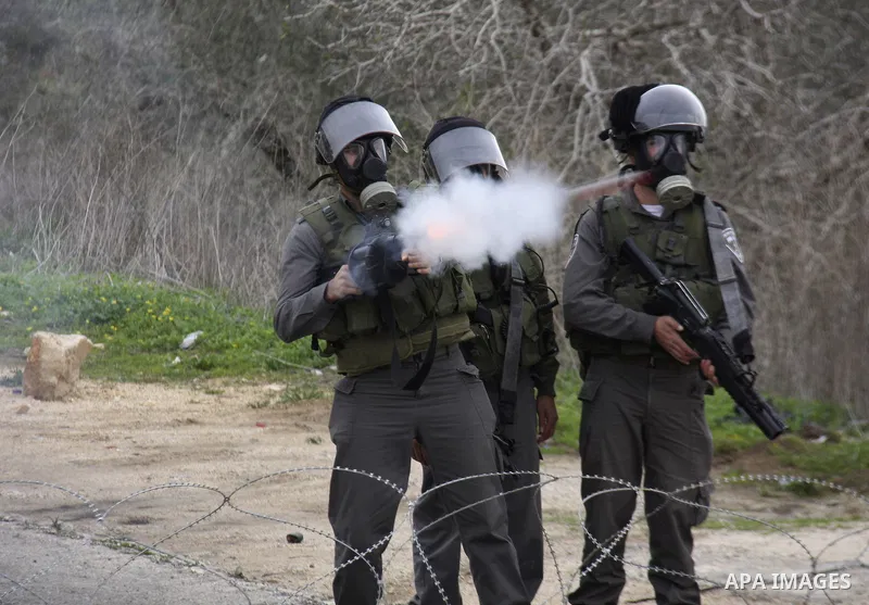 An Israeli soldier fires his weapon at Palestinian youths during a protest against the Jewish settlement of Qadomem, near the West Bank City of Nablus on 30 December 2011. Seven Palestinians were wounded during the clash...