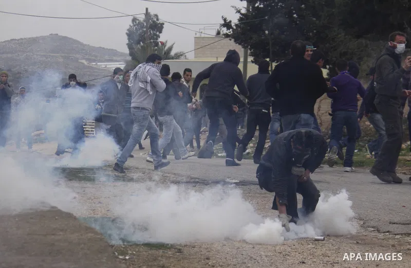 Palestinian protesters run during a protest against the Jewish settlement of Qadomem, near the West Bank City of Nablus on 30 December 2011. Seven Palestinians were wounded during the clashes, medical sources said. Photo...