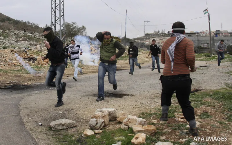 Palestinian protesters run during a protest against the Jewish settlement of Qadomem, near the West Bank City of Nablus on 30 December 2011. Seven Palestinians were wounded during the clashes, medical sources said. Photo...