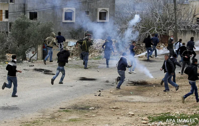 Palestinian protesters run during a protest against the Jewish settlement of Qadomem, near the West Bank City of Nablus on 30 December 2011. Seven Palestinians were wounded during the clashes, medical sources said. Photo...
