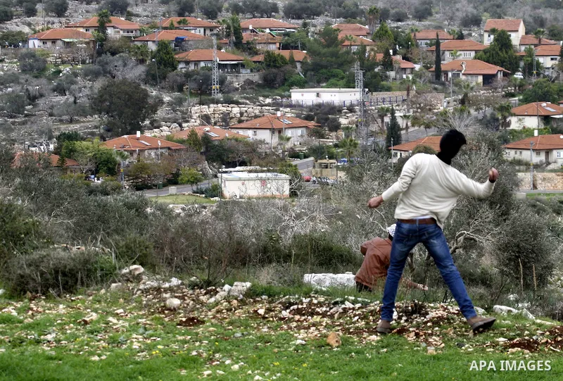 A Palestinian protester hurls stones at Israeli soldiers during a protest against the Jewish settlement of Qadomem, near the West Bank City of Nablus on 30 December 2011. Seven Palestinians were wounded during the clashe...
