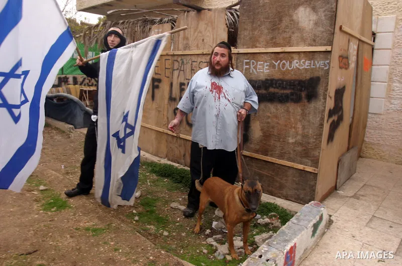 Jewish settlers injured in clashes with Palestinian arab residents of east Jerusalem, Israelis and foreign peace activists hold banners during a protest in the east Jerusalem neighborhood of Sheikh Jarrah, Dec 30, 2011....