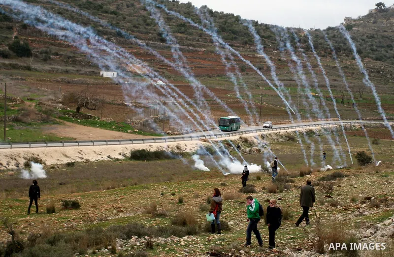 Palestinian protesters runs for cover from tear gas fired by Israeli soldiers during during demonstration against the expansion of the nearby Jewish settlement of Halamish in the West Bank village of Nabi Saleh near Rama...