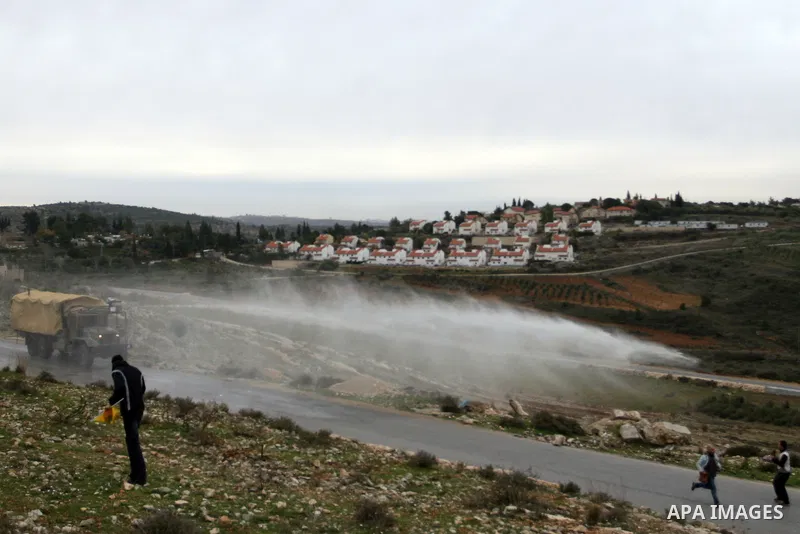 Palestinian protesters runs for cover from tear gas fired by Israeli soldiers during during demonstration against the expansion of the nearby Jewish settlement of Halamish in the West Bank village of Nabi Saleh near Rama...