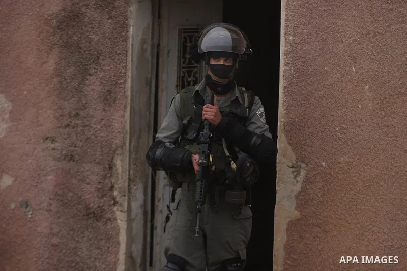 An Israeli soldier fires his weapon at Palestinian youths during demonstration against the expansion of the nearby Jewish settlement of Halamish in the West Bank village of Nabi Saleh near Ramallah, Friday, Dec. 30, 2011...