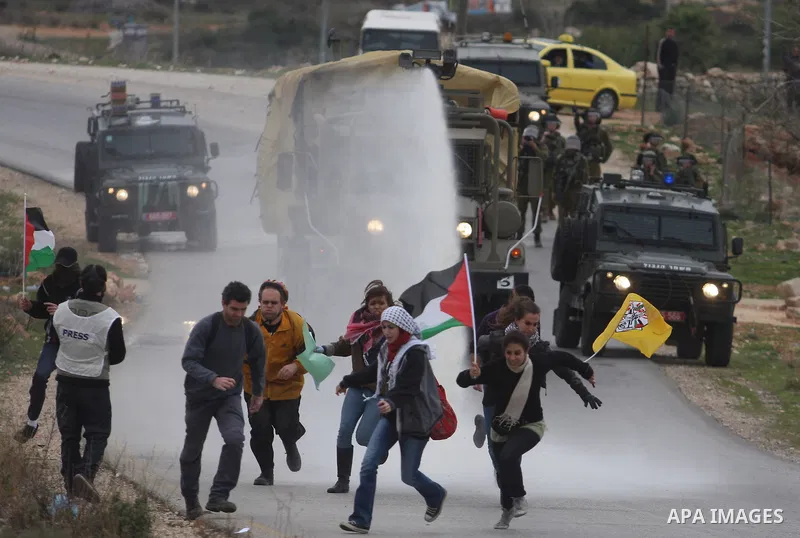 Palestinian protesters runs for cover from tear gas fired by Israeli soldiers during during demonstration against the expansion of the nearby Jewish settlement of Halamish in the West Bank village of Nabi Saleh near Rama...