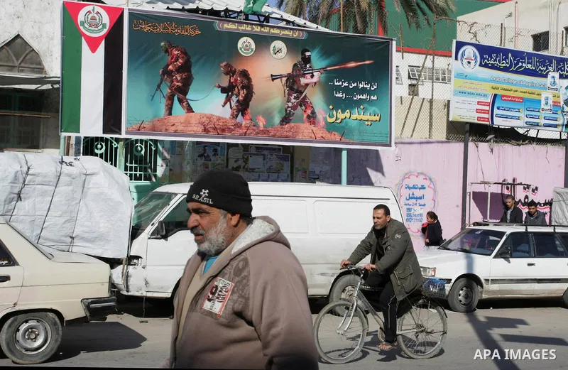 Palestinians walk in front of a billboard Hamas in Rafah refugee camp in the southern Gaza Strip on December 31, 2011.Photo by Abed Rahim Khatib