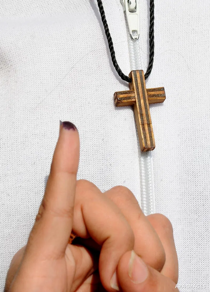 An Egyptian Christian shows her ink-stained finger holding a cross after voting at a polling station in Qaliubia, some 40 kms north of Cairo, on January 4, 2012 as Egyptians headed to the polls again in the final round o...