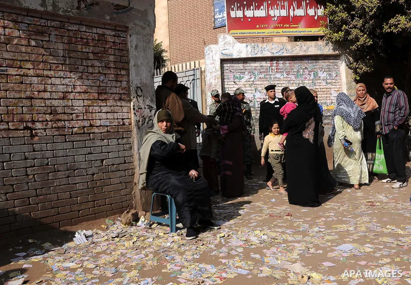 Egyptian women walk on the leaflets of the candidates outside a polling station in Qaliubia, some 40 kms north of Cairo, on January 4, 2012 as Egyptians headed to the polls again in the final round of a phased election t...
