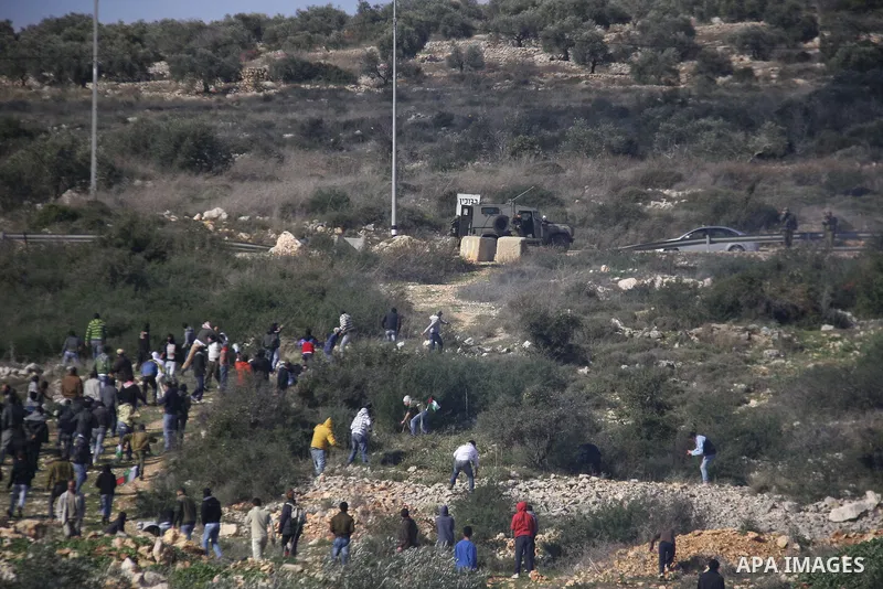 Palestinian and Activists run away from tear gas during a protest against the expansion of the nearby Jewish settlement of Halamish in the West Bank village of Kafer qadum, near Nablus, Friday, Jan. 6, 2012. Photo by Wag...