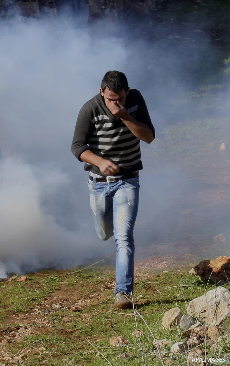 Palestinian and Activists run away from tear gas during a protest against the expansion of the nearby Jewish settlement of Halamish in the West Bank village of Kafer qadum, near Nablus, Friday, Jan. 6, 2012. Photo by Wag...