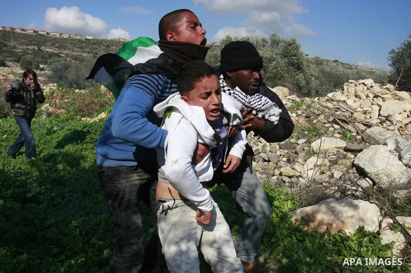Palestinian protesters help a wounded boy during a protest against the expansion of the nearby Jewish settlement of Halamish in the West Bank village of Kafer qadum, near Nablus, Friday, Jan. 6, 2012. Photo by Wagdi Esht...