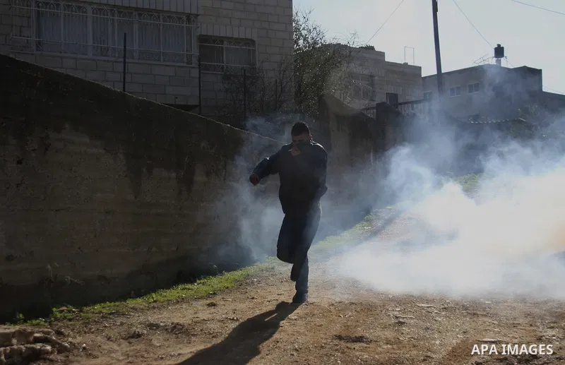 Palestinian and Activists run away from tear gas during a protest against the expansion of the nearby Jewish settlement of Halamish in the West Bank village of Kafer qadum, near Nablus, Friday, Jan. 6, 2012. Photo by Wag...