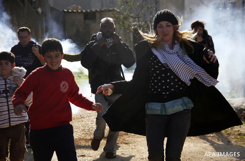 Palestinian and Activists run away from tear gas during a protest against the expansion of the nearby Jewish settlement of Halamish in the West Bank village of Kafer qadum, near Nablus, Friday, Jan. 6, 2012. Photo by Wag...