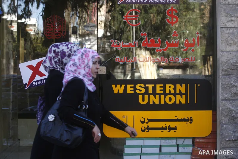 A Palestinian walks past a Western Union office in Gaza City Jan. 9, 2011. The Western Union, a global leader in money tranfer services based in the United States, decided on Tuesday to stop dealing with private offices...