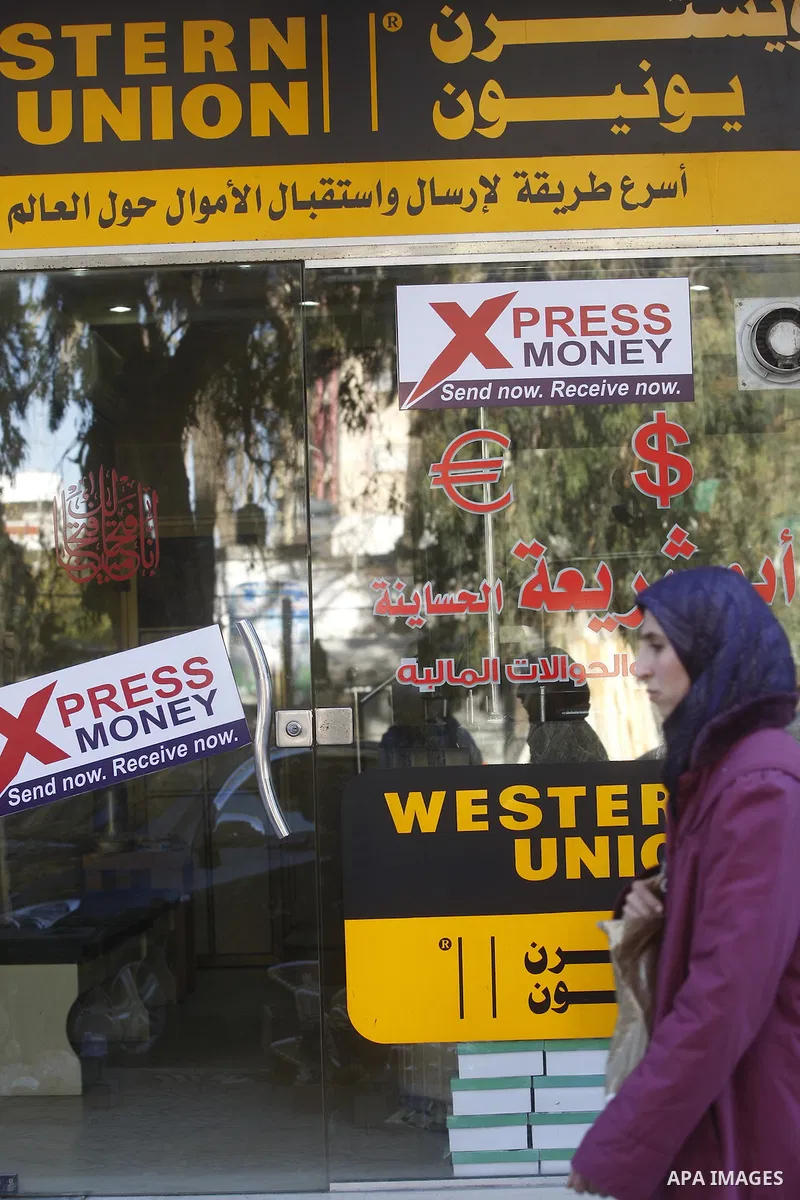 A Palestinian walks past a Western Union office in Gaza City Jan. 9, 2011. The Western Union, a global leader in money tranfer services based in the United States, decided on Tuesday to stop dealing with private offices...